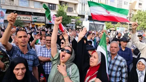مظاهرة حاشدة في إيران، حيث يرفع المشاركون الأعلام ويهتفون، تعبيرًا عن دعمهم للنظام وسط التوترات الإقليمية.