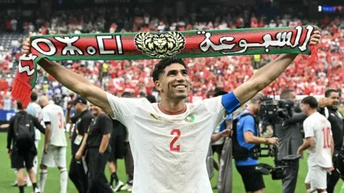 لاعب المنتخب المغربي يرفع وشاح "السبوعة" احتفالاً بتأهل المغرب إلى ربع نهائي كأس العالم FIFA 2026، وسط أجواء حماسية في الملعب.