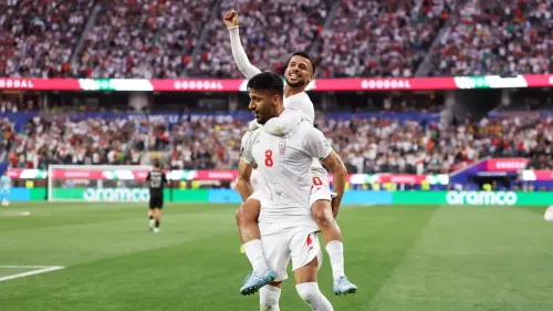 فرحة لاعبي المنتخب الإيراني بعد تسجيل هدف، مع تواجد جماهير حماسية في المدرجات خلال مباراة مهمة.