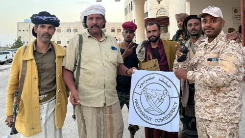 مجموعة من الرجال اليمنيين يحملون علم "اتحاد حضرموت" في المكلا، يعكسون التوترات السياسية والعسكرية في المنطقة بعد الضربة السعودية.