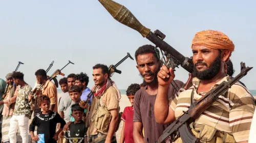 مسلحون حوثيون يحملون أسلحة ثقيلة وخفيفة في صف على الساحل، في سياق إعلان الحوثيين فرض حصار بحري على السعودية في البحر الأحمر.
