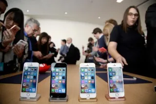 عرض لعدد من هواتف iPhone 16 و15 Pro و15 Pro Max في حدث ترويجي، مع حشد من الزوار يتفقدون الأجهزة.