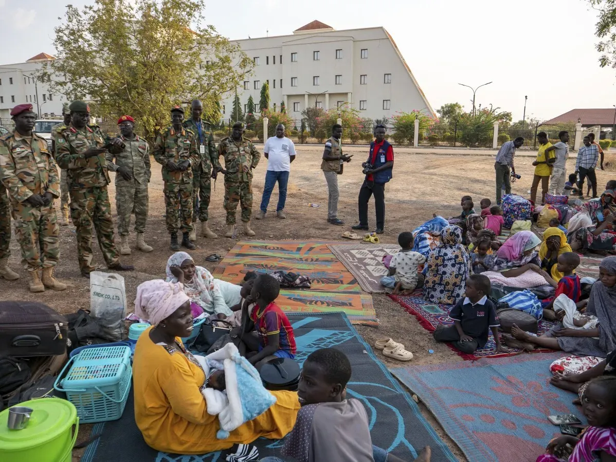 جنود من الجيش في جوبا، جنوب السودان، يراقبون مجموعة من المدنيين الجالسين على الأرض، وسط أجواء من التوتر بعد حوادث العنف.