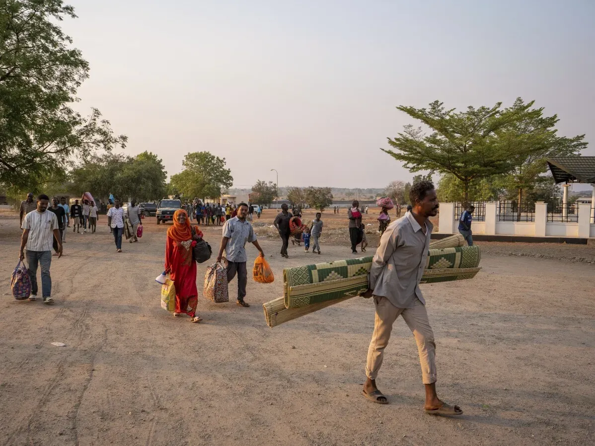 لاجئون يحملون أمتعتهم في جوبا، جنوب السودان، بينما يتجهون نحو مناطق أكثر أمانًا بعد أعمال العنف والنهب التي تعرضت لها المحلات التجارية.