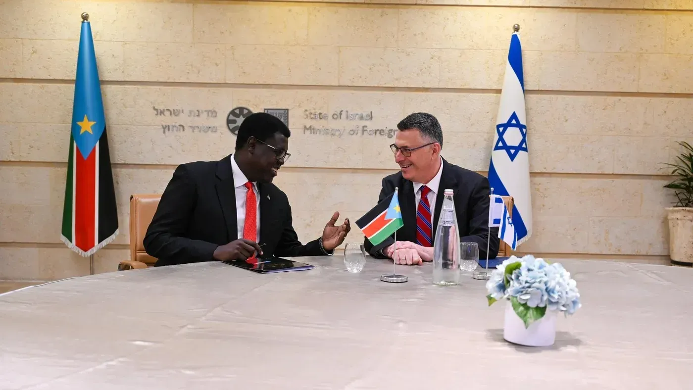 اجتماع بين ممثلين من جنوب السودان وإسرائيل، مع العلمين الوطنيين في الخلفية، يناقشون قضايا تتعلق باللاجئين الفلسطينيين.