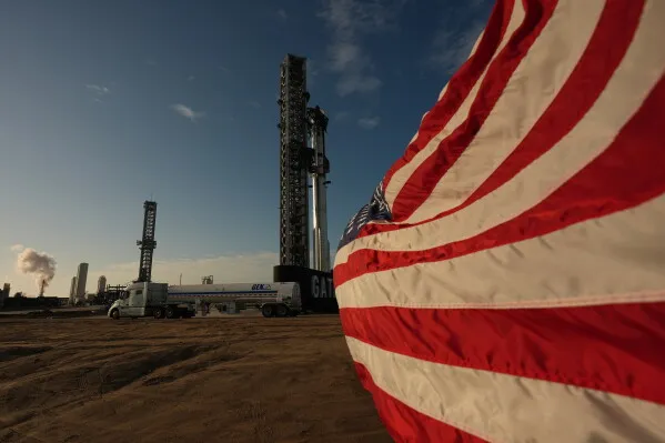 صاروخ Starship الجديد من SpaceX يقف بجانب علم الولايات المتحدة، مستعداً للإطلاق في اختبار تاريخي نحو الفضاء.