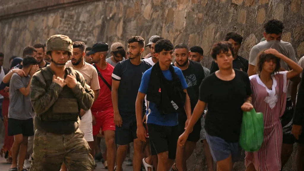 مجموعة من المهاجرين الشباب يسيرون بجانب جندي إسباني في سبتة خلال أزمة الهجرة التي شهدتها المدينة على الحدود مع المغرب.