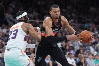 لاعب من سان أنطونيو سبيرز يستحوذ على الكرة بينما يحاول لاعب من فينيكس صنز الدفاع عنه، خلال مباراة كرة سلة حماسية.