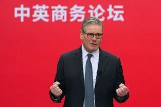 كير ستارمر، رئيس الوزراء البريطاني، يتحدث في منتدى تجاري في شنغهاي، مع خلفية حمراء تحمل نصًا باللغة الصينية، في إطار تعزيز العلاقات الاقتصادية بين بريطانيا والصين.