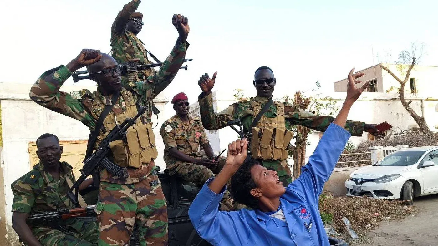 جنود من الجيش السوداني يحتفلون بعد استعادة السيطرة على مدينة ود مدني، بينما يظهر أحدهم يرفع يده في علامة النصر.