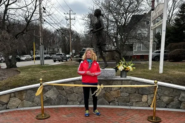 تمثال برونزي لامرأة تجري، يمثل Bobbi Gibb، أول امرأة تشارك في ماراثون بوسطن، يقف بجوارها في موقع الكشف عنه.