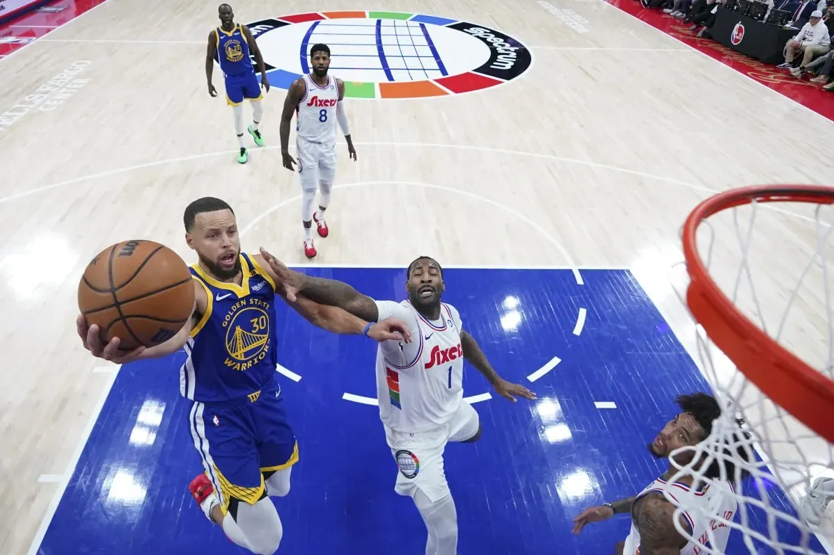 ستيف كاري يسجل رمية دانك ضد فريق 76ers، مع وجود لاعبين آخرين في الملعب، في مباراة مثيرة ضمن دوري كرة السلة الأمريكي.