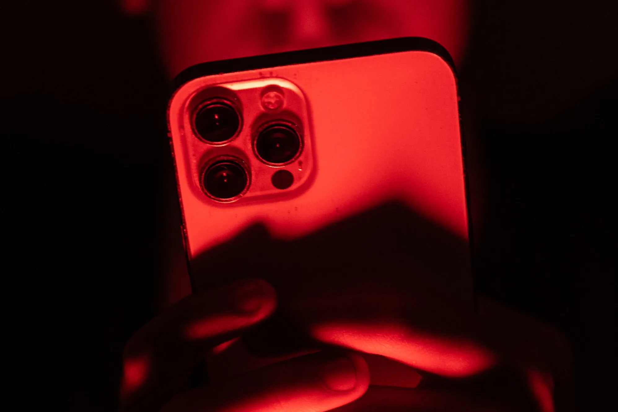 هاتف آيفون مضاء بضوء أحمر يعكس أهمية تحديث نظام iOS لحماية الأجهزة من ثغرات أمنية خطيرة في iOS 26.
