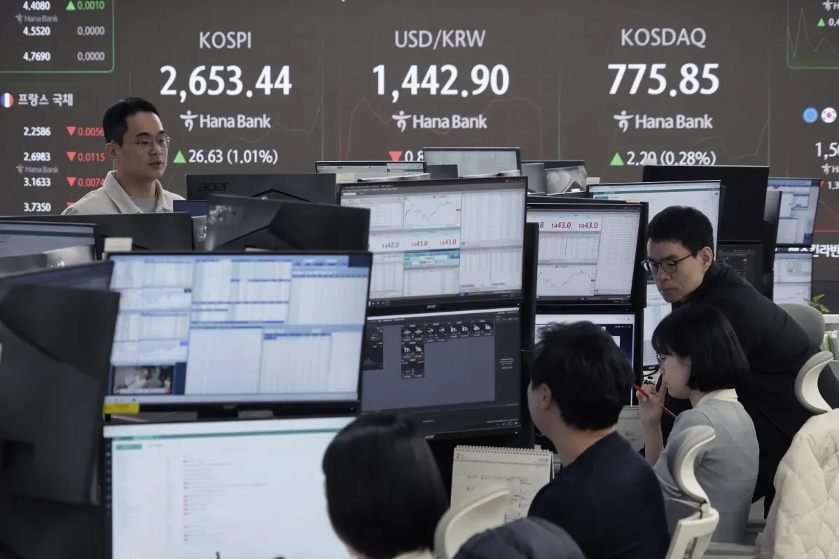 متداولون في غرفة تداول مع شاشات تعرض مؤشرات الأسهم وأسعار العملات، في سياق تباين أداء الأسواق الآسيوية.