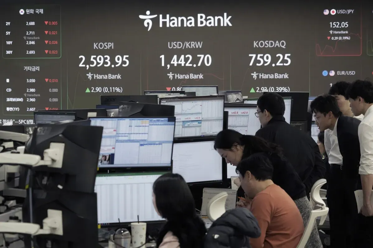 تداولات نشطة في مكتب Hana Bank مع شاشات تعرض مؤشرات الأسهم وأسعار العملات، وسط مراقبة المستثمرين لأداء الأسواق.