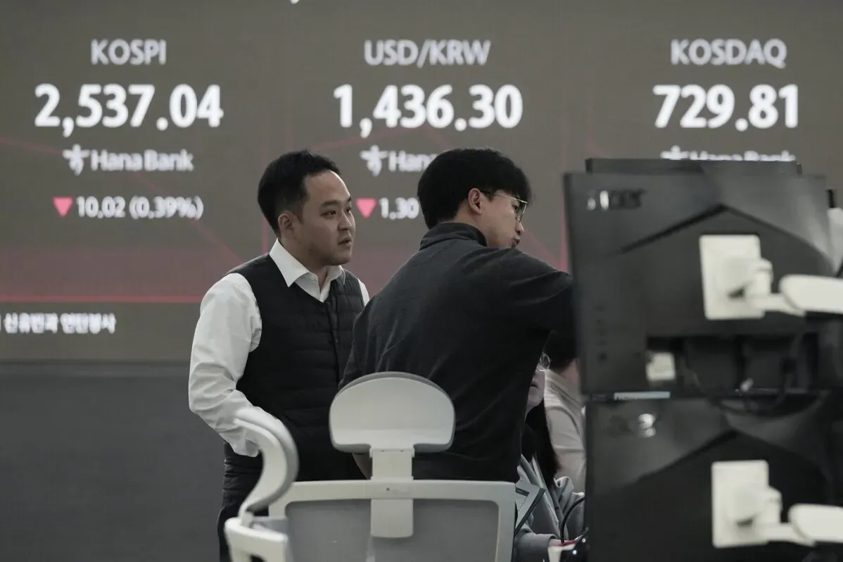 رجال يرتدون بدلات في بورصة آسيوية، حيث تُعرض مؤشرات الأسهم مثل Kospi وKOSDAQ