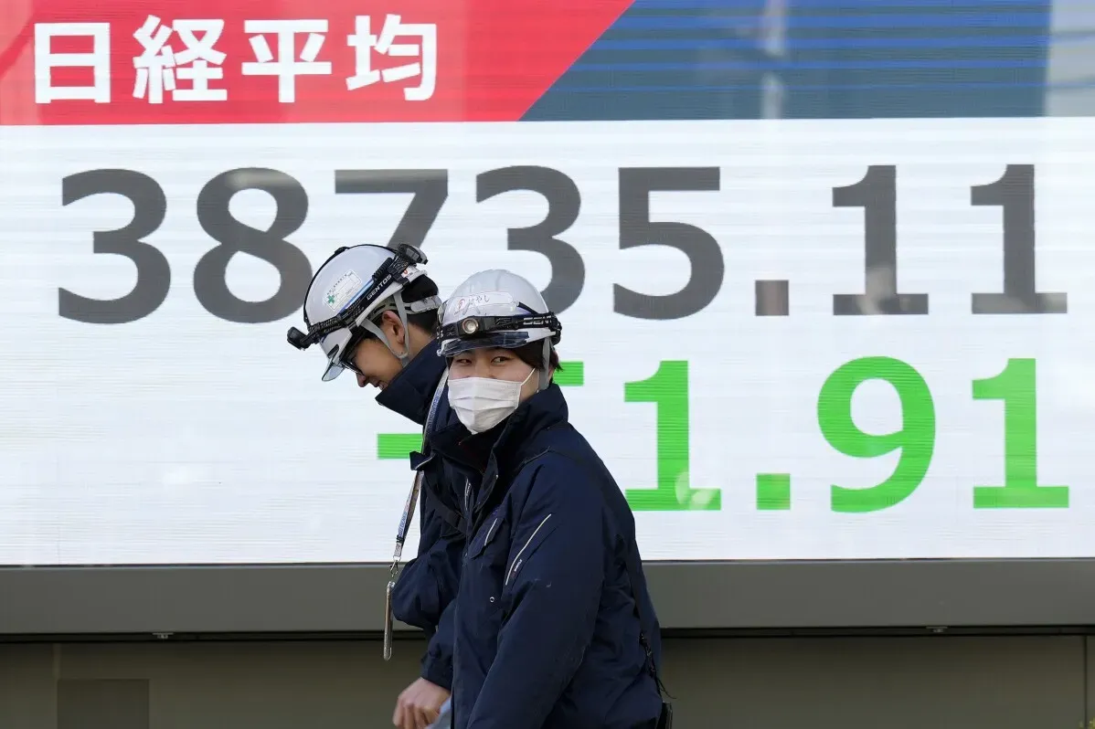 مستثمرون يمرون أمام شاشة تعرض مؤشر نيكاي 225 في طوكيو، حيث انخفض بنسبة 0.1% إلى 38,735.11.