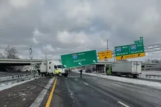 شاحنة متوقفة على طريق مغطى بالجليد، مع لافتات إرشادية متضررة تشير إلى ناشفيل، تعكس آثار العاصفة الجليدية في المنطقة.