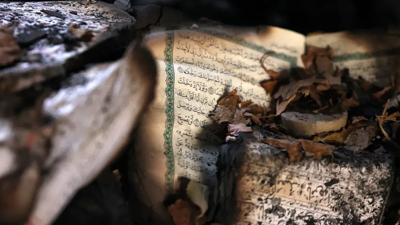 صفحة من القرآن الكريم متضررة ومغطاة بأوراق الشجر، تعكس آثار الاضطرابات في إيران خلال الاحتجاجات الأخيرة.