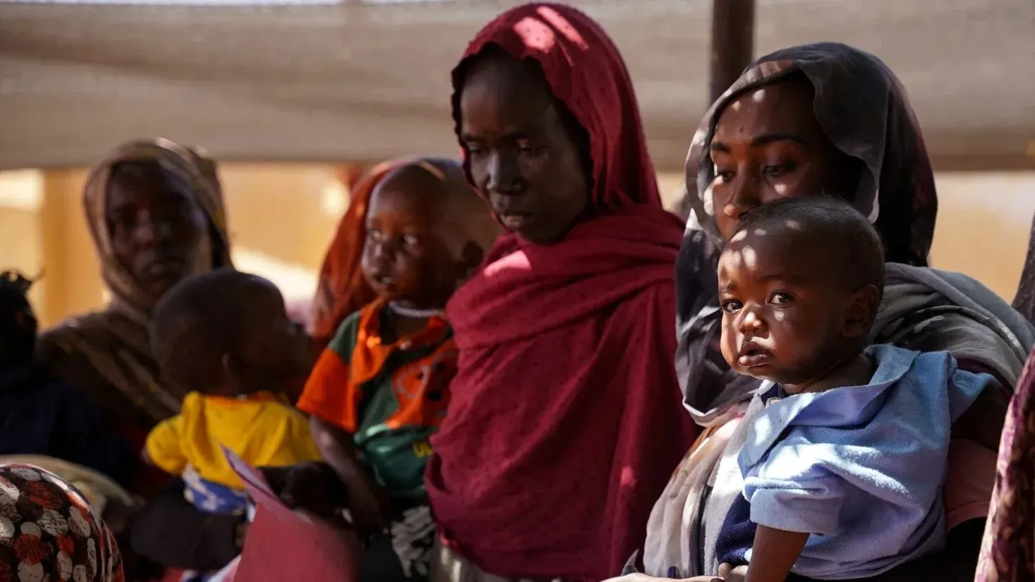 نساء وأطفال في مخيم للنازحين بالسودان، يعكسون الأزمة الإنسانية المتفاقمة مع ارتفاع معدلات الجوع وسوء التغذية.