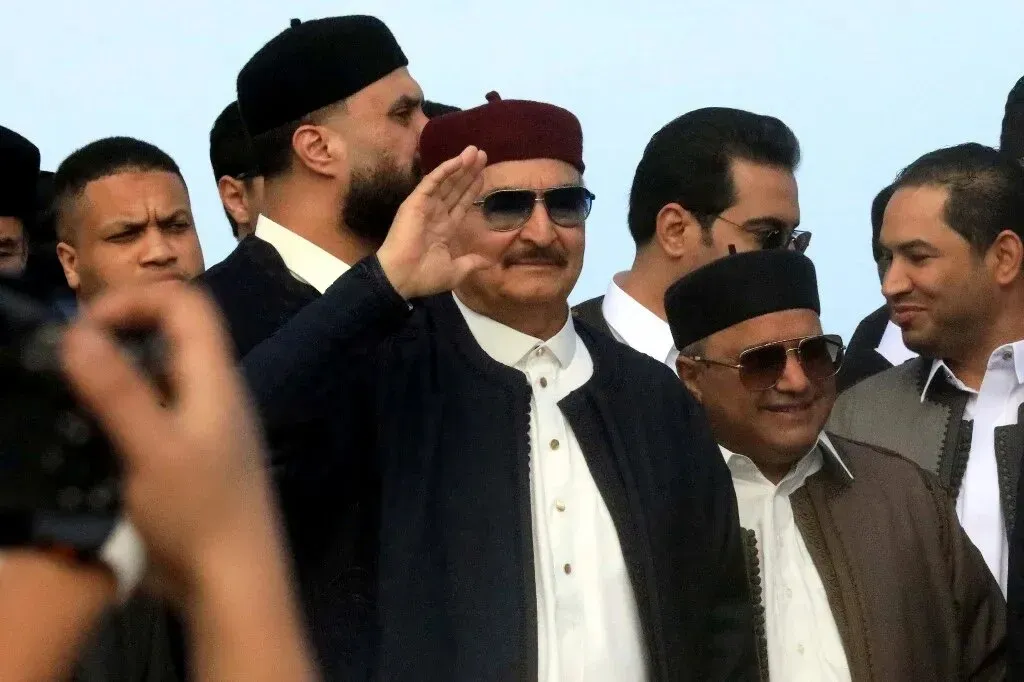 قائد الميليشيا الليبية خليفة حفتر يلوح بيده وسط مجموعة من الأشخاص، في سياق التوترات الحدودية بين السودان وليبيا.