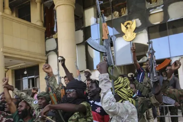 جنود من الجيش السوداني يحتفلون أمام مبنى حكومي بعد استعادة السيطرة عليه، حاملين أسلحتهم ويرتدون زيهم العسكري.