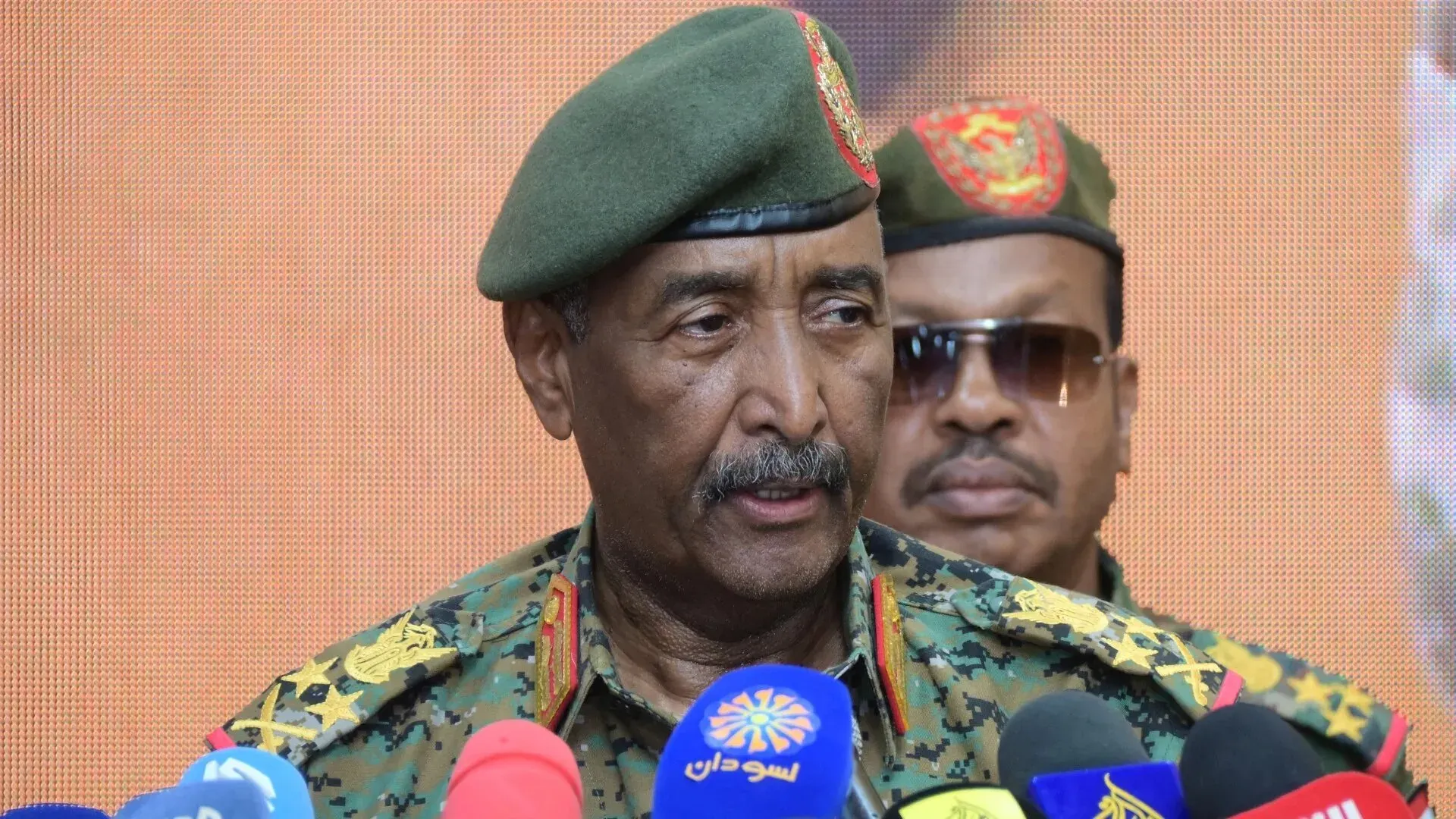 صورة لقائد القوات المسلحة السودانية يتحدث في مؤتمر صحفي، مع التركيز على التوترات العسكرية والسياسية في السودان.