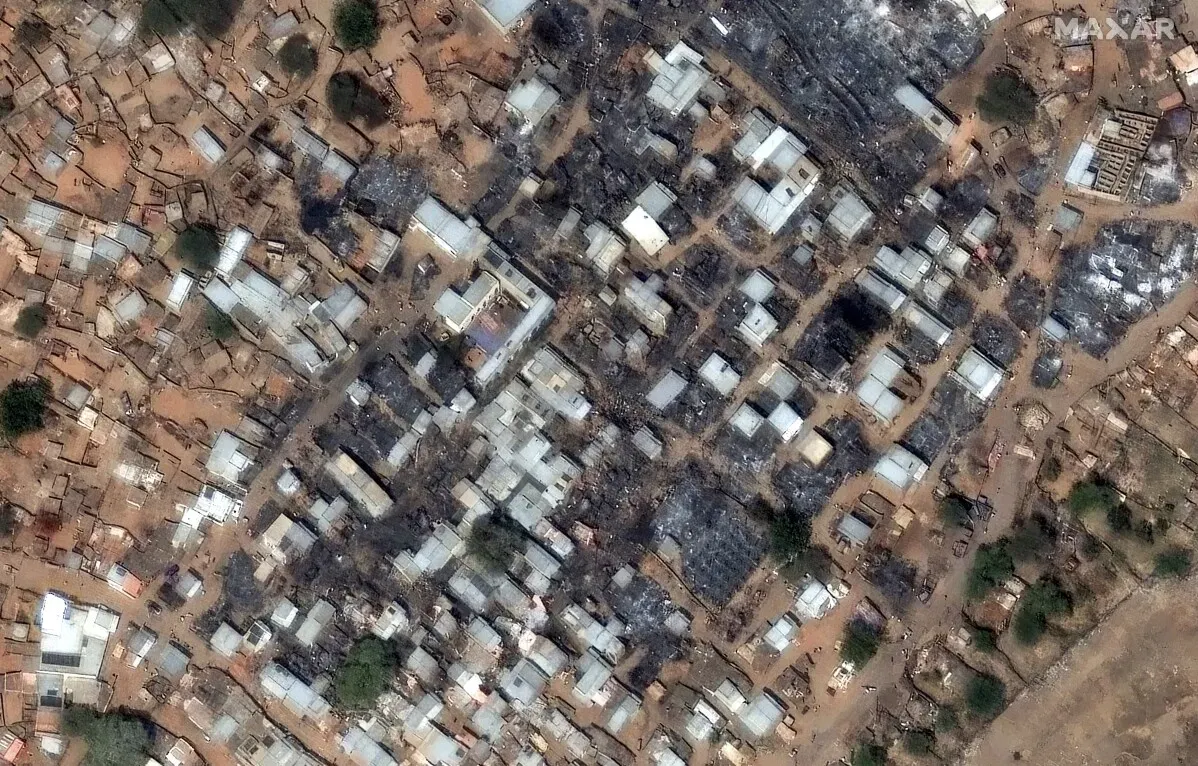 صورة جوية تظهر الأضرار الواسعة في منطقة سكنية في السودان بعد النزاع، مع بيوت مدمرة وأرض محروقة، تعكس آثار الحرب المستمرة.