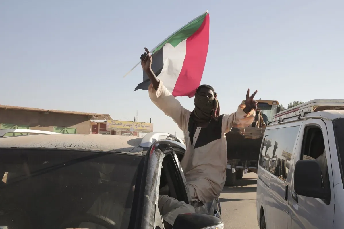 شخص يحمل علم السودان ويعبر عن الفرح بعد استعادة الجيش السيطرة على مدينة ود مدني من قوات الدعم السريع.