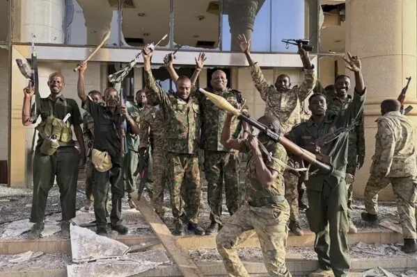 جنود سودانيون يحتفلون داخل القصر الجمهوري بعد استعادته، مع أسلحة في أيديهم، في مشهد يعكس انتصار الجيش في الصراع المستمر.