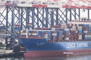 سفينة شحن تحمل حاويات في ميناء، تعكس تأثير الرسوم الجمركية على التجارة العالمية بعد حكم المحكمة العليا الأمريكية.