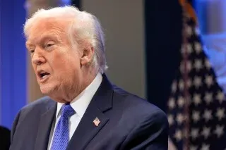 ترامب يتحدث في مؤتمر صحفي بعد قرار المحكمة العليا بإلغاء تعريفاته الجمركية، مع العلم الأمريكي خلفه.