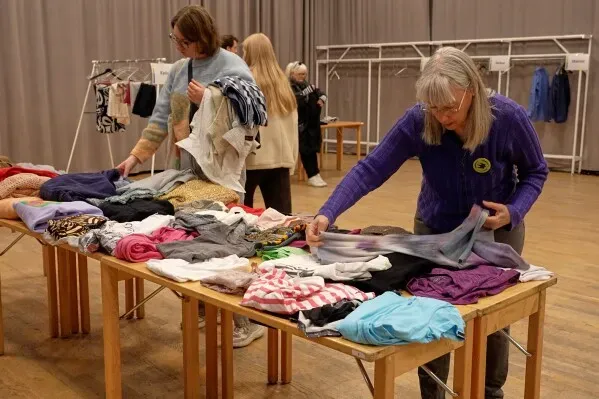 نساء يتبادلن الملابس المستعملة في فعالية لتقليل الأثر البيئي لصناعة الأزياء، في مركز مجتمعي في ستوكهولم.