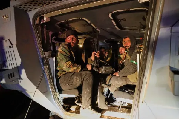 مقاتلون يجلسون داخل مركبة عسكرية، مع استعدادات لوقف إطلاق النار في حلب، وسط أجواء من التوتر بعد الاشتباكات الأخيرة.