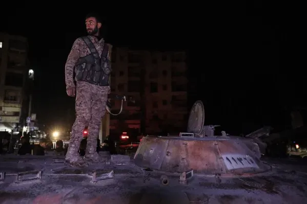 مقاتل يقف على دبابة في حلب ليلاً، وسط أجواء من التوتر بعد إعلان وقف إطلاق النار بين القوات الحكومية والمقاتلين الأكراد.