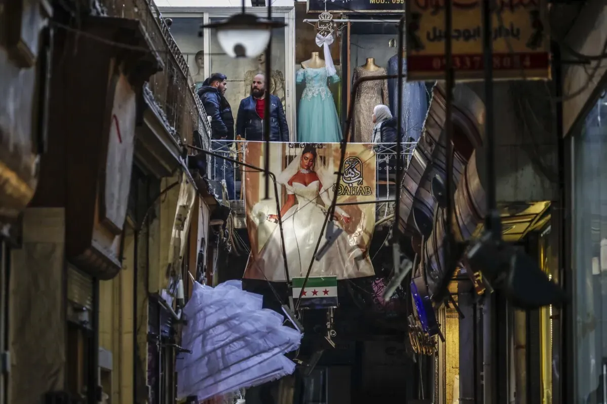 سوق قديم مزدحم في دمشق، حيث يتجمع الناس بين الأكشاك، وتظهر ملابس وأزياء عازفي مشهورة. شعور احتفالي مع عدم وجود مشتريات.