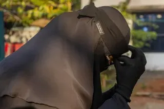 امرأة ترتدي النقاب الأسود وتظهر مشاعر القلق، في سياق تحقيق حول تجنيد العمال البنغلاديشيين للقتال في أوكرانيا.