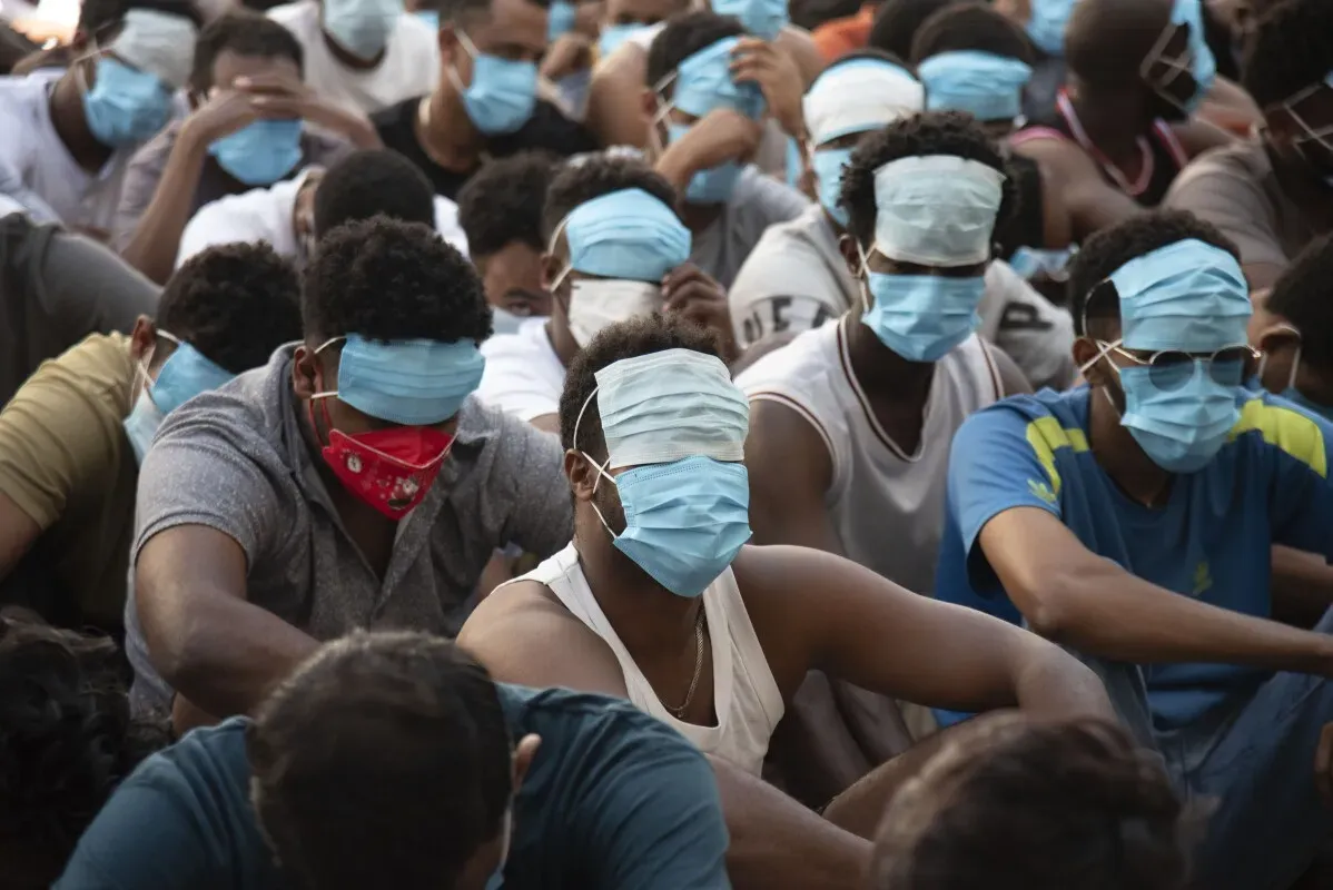 آلاف الأشخاص المحتجزين في ظروف غير إنسانية، يرتدون أقنعة جراحية، يجلسون في صفوف متراصة بانتظار الإفراج عنهم من مراكز الاحتيال في ميانمار.