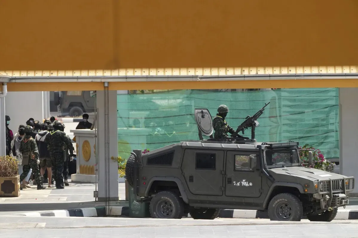 جنود مسلحون في سيارة عسكرية يقفون بالقرب من مجموعة من الأشخاص الذين تم تحريرهم من مراكز الاحتيال في تايلاند، وسط إجراءات أمنية مشددة.