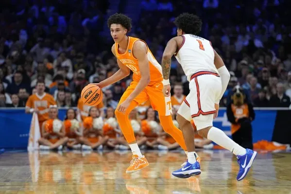 لاعب كرة سلة من فريق تينيسي يت dribble الكرة أثناء مواجهة لاعب من فريق فيرجينيا في مباراة حاسمة ضمن بطولة NCAA.