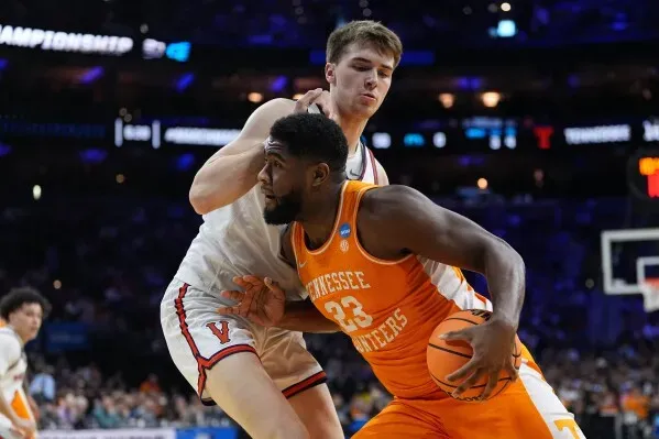 لاعب تينيسي يحمل الكرة ويتجاوز مدافع فيرجينيا في مباراة حماسية ضمن بطولة NCAA، مع التركيز على الأداء القوي للفريق.