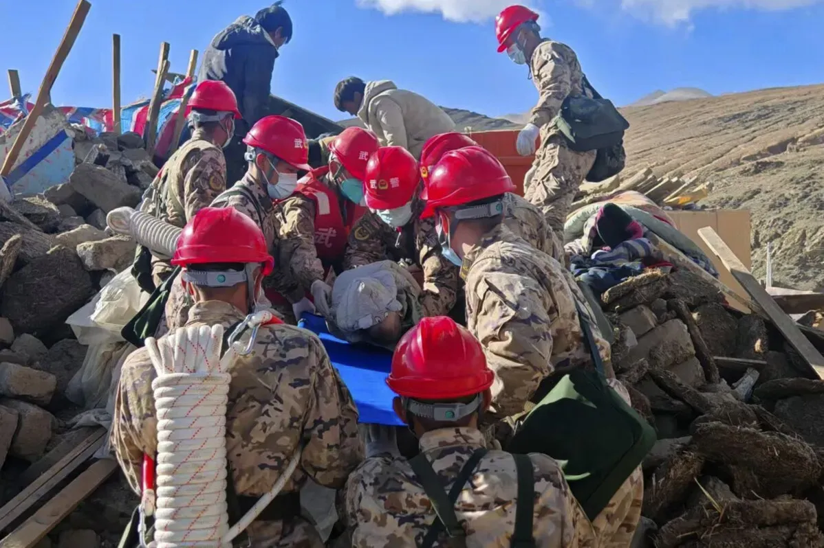 عمال الإنقاذ يرتدون خوذات حمراء أثناء البحث عن ناجين تحت أنقاض المنازل المدمرة جراء الزلزال في التبت.