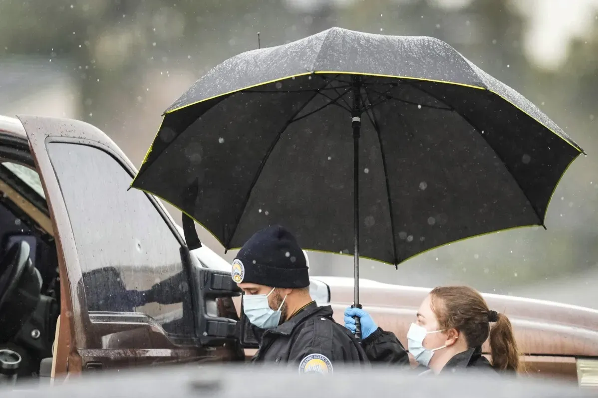 ضابطان يرتديان أقنعة واقية يحملان مظلة أثناء البحث عن المشتبه به في حادثة إطلاق نار في هيوستن.