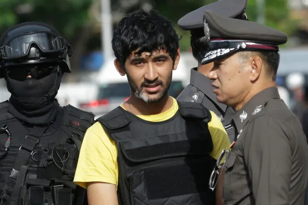 رجل من أقلية الإيغور يرتدي سترة واقية، محاطاً برجال شرطة، بعد صدور حكم بالإعدام عليه في قضية تفجير بانكوك عام 2015.