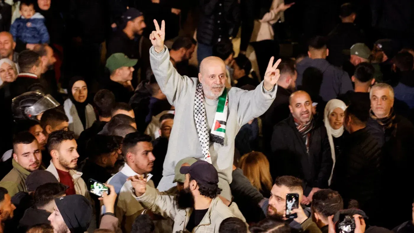 احتفالات فلسطينية بمناسبة الإفراج عن معتقلين سابقين، يظهر رجال يحتفلون بإشارات النصر وسط حشود من الناس.