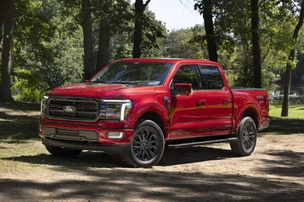 شاحنة فورد F-150 حمراء اللون متوقفة في منطقة طبيعية، تُظهر تصميمها القوي ومميزاتها المثالية للتخييم، مثل نظام Pro Power Onboard.