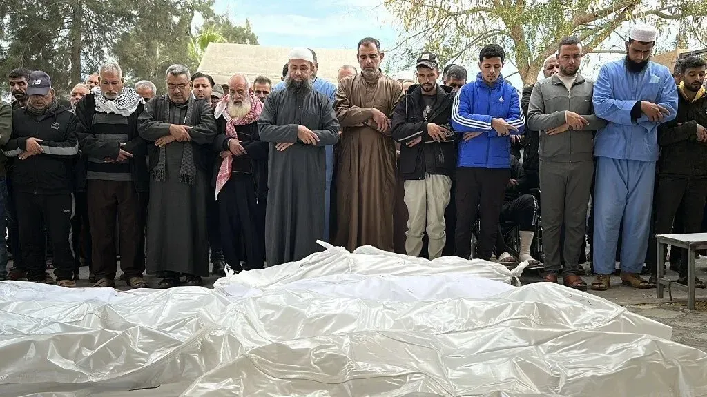 تجمع رجال في خان يونس لتأدية صلاة الجنازة على ضحايا الغارات الجوية، مع تغطية الجثث بأغطية بيضاء، مما يعكس الفقدان الكبير في العائلات.