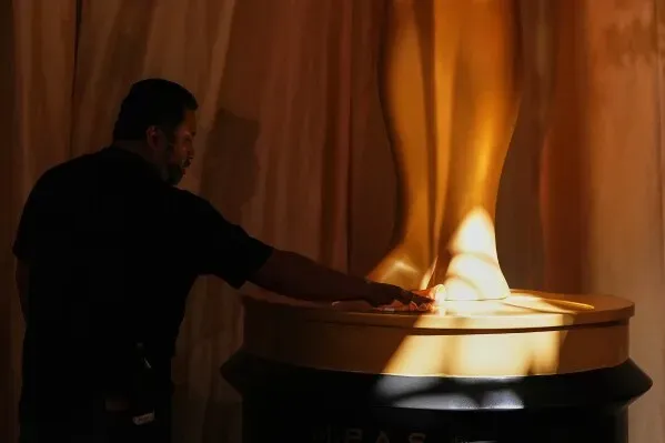 رجل يلمس قاعدة تمثال الأوسكار الذهبي في مسرح دولبي، مع إضاءة خافتة تبرز تفاصيل التمثال قبل حفل توزيع الجوائز.