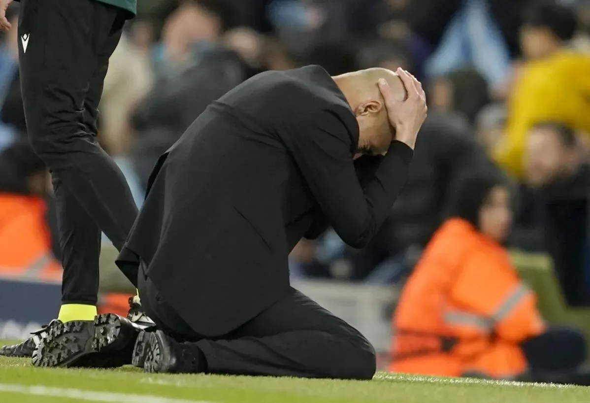 بيب جوارديولا، مدرب مانشستر سيتي، يجلس على الأرض ويضع يديه على رأسه، تعبيرًا عن الإحباط بعد مباراة كبيرة في دوري أبطال أوروبا ضد ريال مدريد.