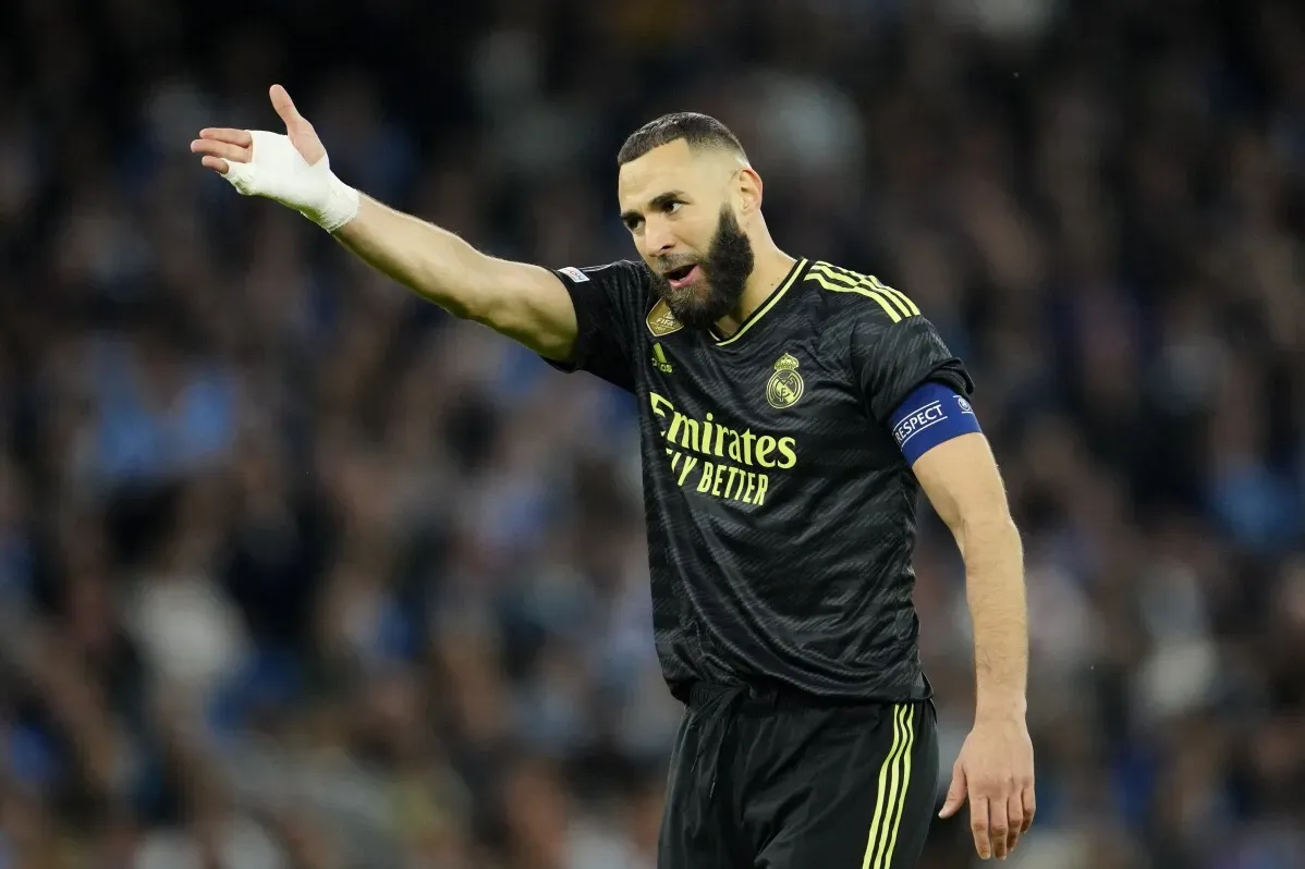 لاعب ريال مدريد كريم بنزيمة يوجه التعليمات خلال مباراة كرة القدم. يُظهر الخلفية مدرجات مليئة بالجماهير.